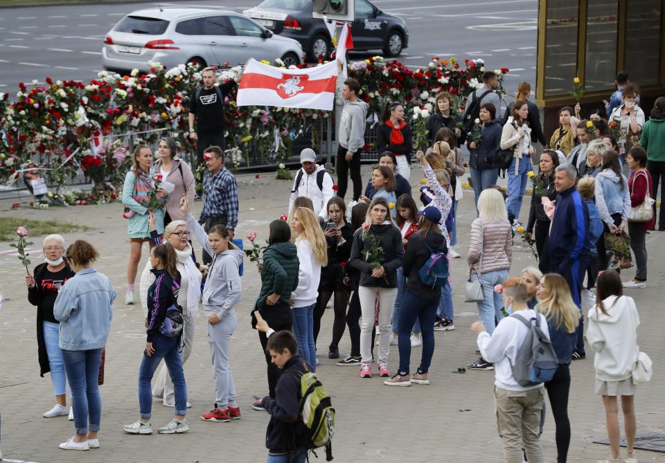 CORRECTING COUNTRY IN CAPTION TO BELARUS - People with Belarusian National flag gather at the place where a protester died amid the clashes protesting the election results in Minsk, Belarus, Wednesday, Aug. 12, 2020. The demonstrators are contesting the official count showing President Alexander Lukashenko winning a sixth term with 80% of Sunday's vote, with crowds taking to the streets every night since to demand a recount. (AP Photo)