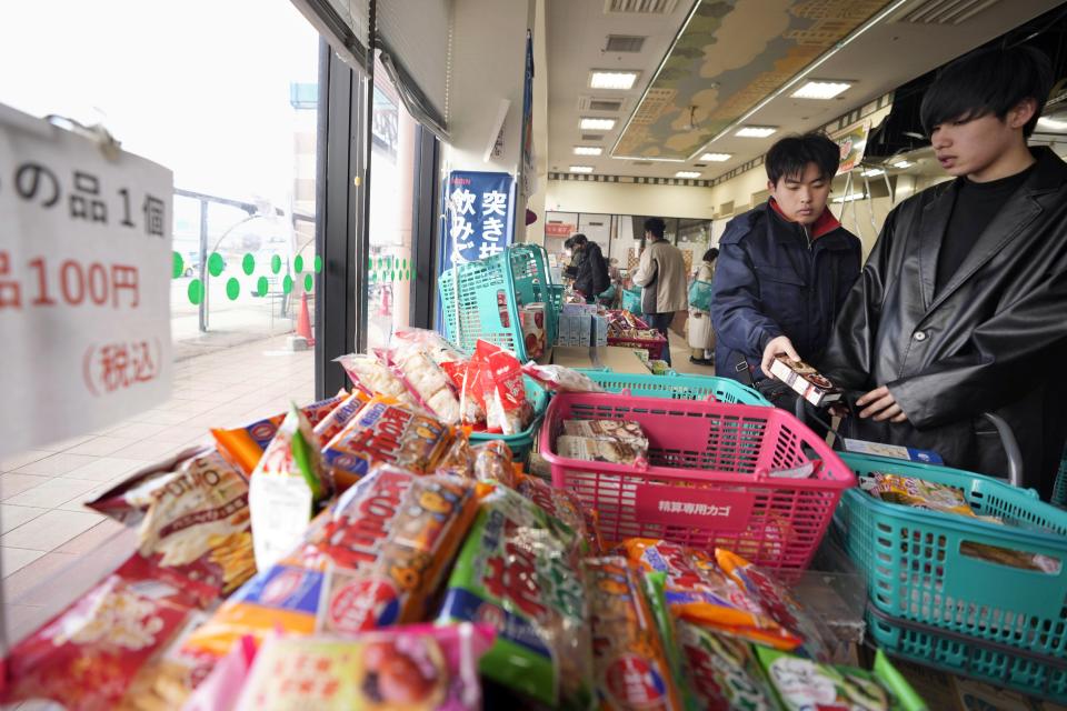 People shop for food items at a supermarket that has offered some food and other items for 100 yen (about $U.S. 70 cents) for each, in Wajima in the Noto peninsula, facing the Sea of Japan, northwest of Tokyo, Saturday, Jan. 6, 2024, following Monday's deadly earthquake. The sign, left, reads, "100 yen (about $U.S. 70 cents) for each item." (AP Photo/Hiro Komae)