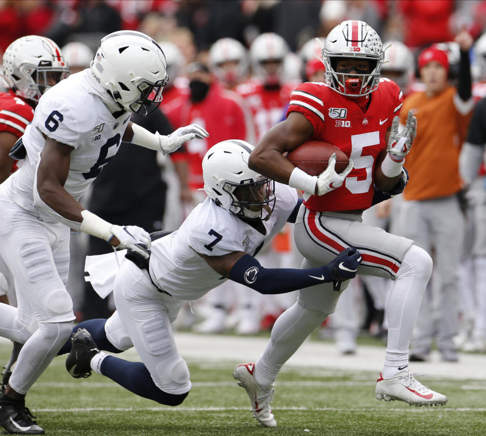 Ohio State receiver Garrett Wilson, right, runs after a catch as Penn State defenders Cam Brown, left, and Jaquan Brisker make the tackle during the first half of an NCAA college football game Saturday, Nov. 23, 2019, in Columbus, Ohio. (AP Photo/Jay LaPrete)