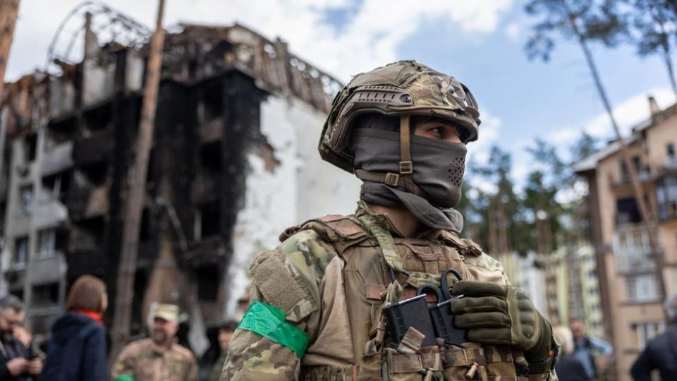 Un soldado ucraniano frente a un edificio destruido.