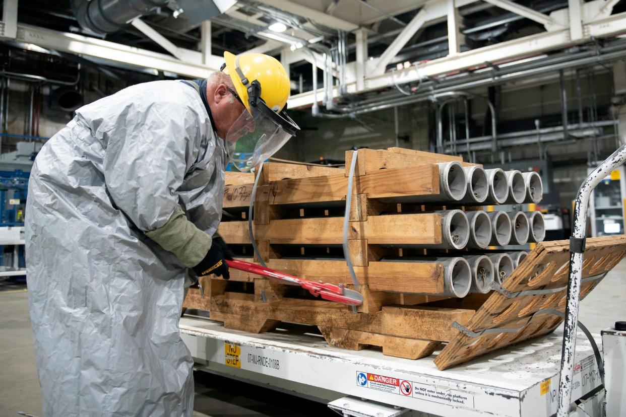 An operator wearing protective gear cuts the metal bands on a pallet of M55 rockets containing GB (sarin) nerve agent on July 6, 2022, at the Blue Grass Army Depot near Richmond, Ky.