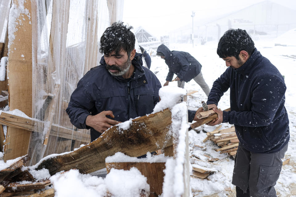 Migrants handle firewood at the Lipa camp, outside Bihac, Bosnia, Friday, Jan. 8, 2021. A fresh spate of snowy and very cold winter weather on has brought more misery for hundreds of migrants who have been stuck for days in a burnt out camp in northwest Bosnia waiting for heating and other facilities. (AP Photo/Kemal Softic)