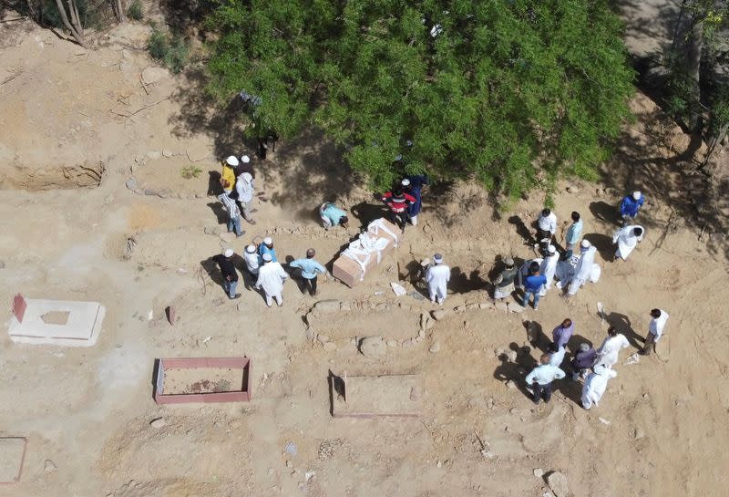 Una imagen tomada con un dron muestra a los familiares esperando antes de enterrar los cuerpos de los hombres que murieron debido a la enfermedad del coronavirus (COVID-19), en un cementerio de Nueva Delhi, India