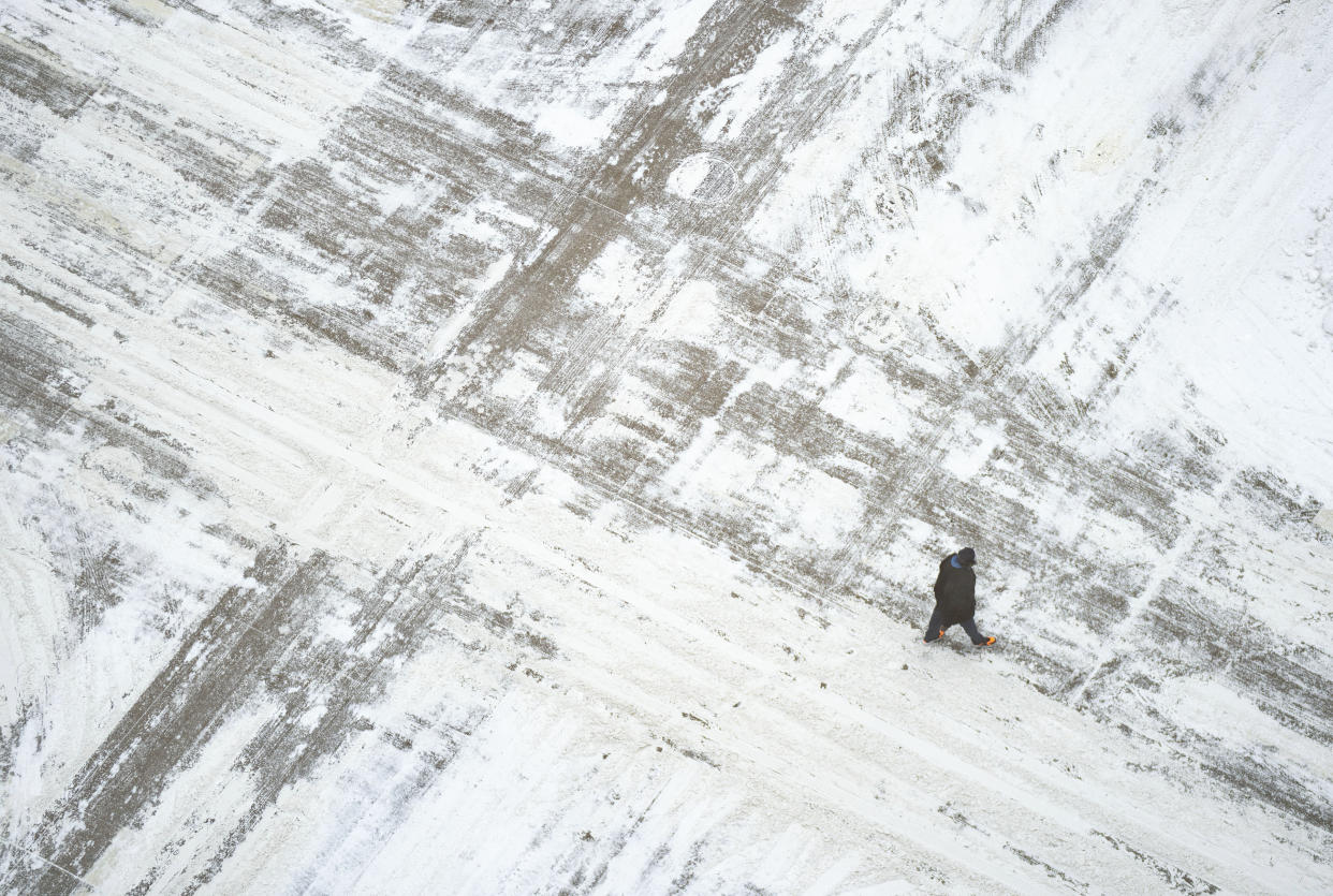 A man crosses a snow covered S. Sixth St. Wednesday, Feb. 22, 2023 in downtown Minneapolis. (Alex Kormann/Star Tribune via AP)