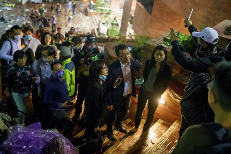 Teachers and relatives negotiate with protesters about the surrender of younger students from the occupied campus of the Hong Kong Polytechnic University that is surrounded by police in Hong Kong