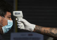 Un trabajador de la ciudad mide la temperatura de un hombre antes de ingresar al centro comercial Apumanque, en el barrio de Las Condes, en Santiago de Chile, el jueves 30 de abril de 2020. (Foto AP/Esteban Félix)