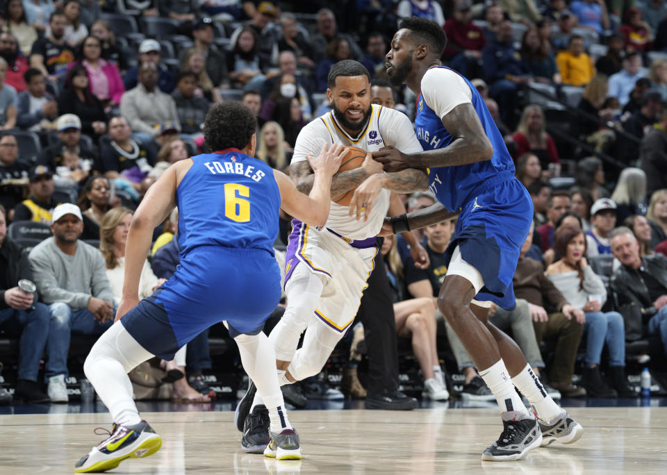 Los Angeles Lakers guard D.J. Augustin, center, drives to the rim between Denver Nuggets guard Brynn Forbes, left, and forward Jeff Green in the first half of an basketball game Sunday, April 10, 2022, in Denver. (AP Photo/David Zalubowski)