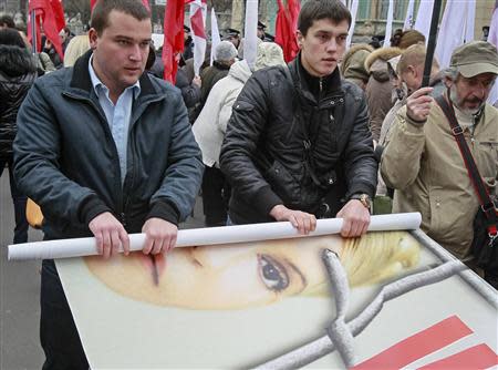 Opposition supporters roll a banner with the portrait of jailed former prime minister Yulia Tymoshenko after a rally in front of the Parliament building in Kiev November 13, 2013. . REUTERS/Gleb Garanich