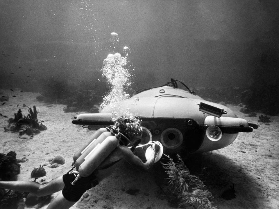 A diver and a two-man submarine search the ocean in 1963.