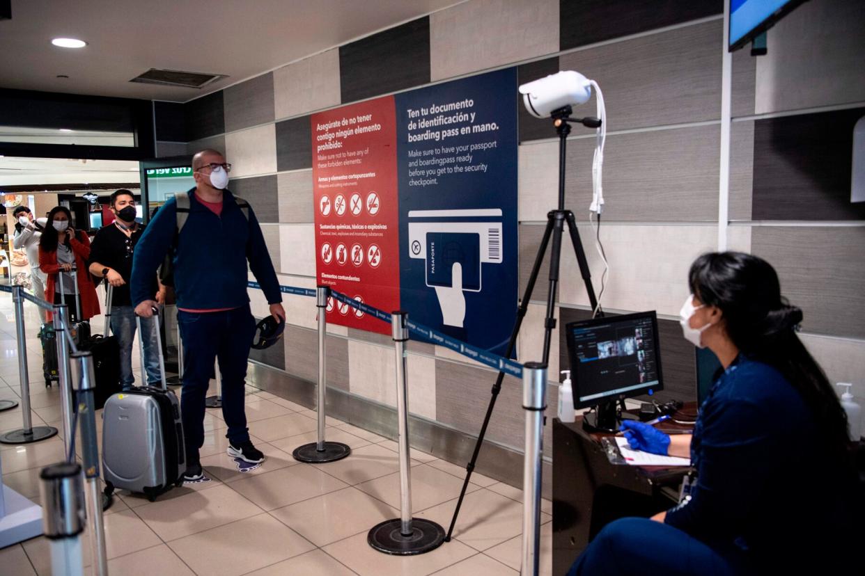 A Chile's Health Ministry worker monitors a screen of a thermal scanner to check body temperature of a passenger before boarding a flight at Santiago International Airport