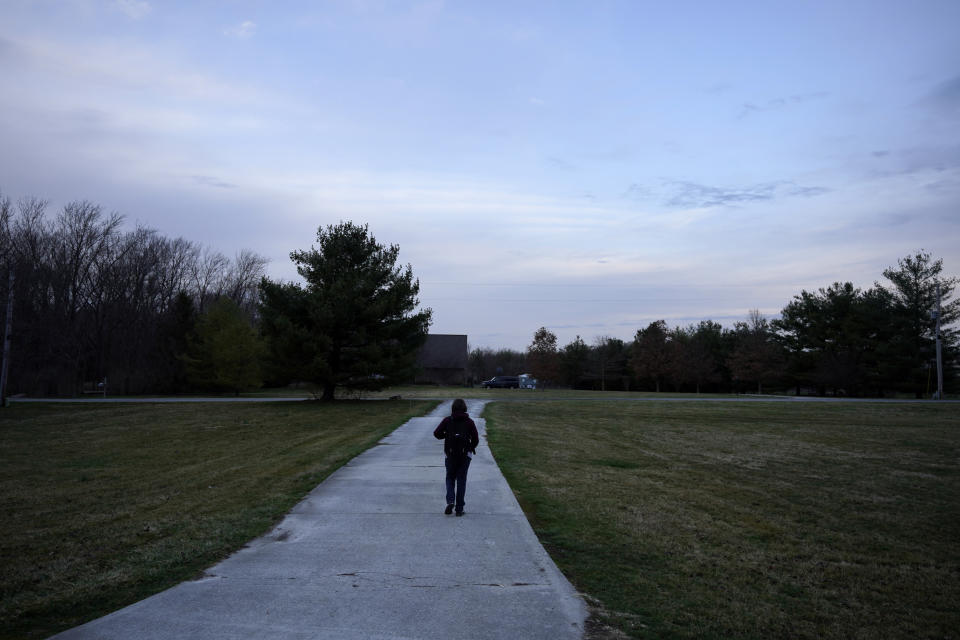 Kari Wegg's oldest son, Gavin, walks down the long rural driveway in the early morning hours to catch a bus for school outside the family's Westfield, Ind., home on Tuesday, March 23, 2021. (AP Photo/Charles Rex Arbogast)