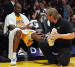 Lakers guard Kobe Bryant receives help from a trainer during a timeout in a game against the Houston Rockets on April 6 in Los Angeles. (Photo by Harry How/Getty Images)