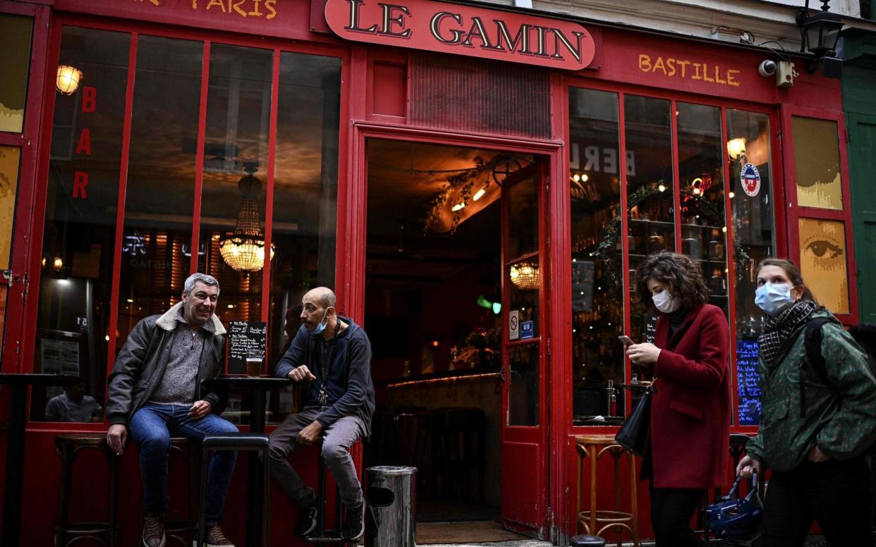 People have a drink as they sit on the terrace of a bar in the French capital Paris on October 3, 2020. - CHRISTOPHE ARCHAMBAULT/ AFP