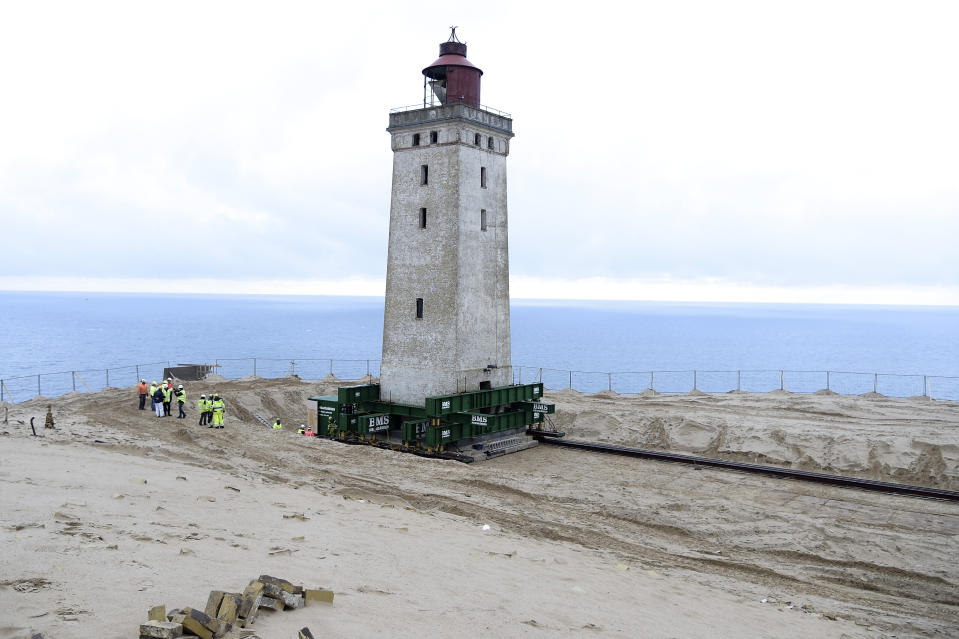 The Rubjerg Knude Lighthouse is being moved in Jutland, Denmark, Tuesday, Oct. 22, 2019. A 120-year-old lighthouse has been put on wheels and rails to attempt to move it some 80 meters (263 feet) away from the North Sea, which has been eroding the coastline of northwestern Denmark. When the 23-meter (76 feet) tall Rubjerg Knude lighthouse was first lit, in 1990, it was roughly 200 meters (656 feet) from the coast; now it is only about 6 meters away. (Henning Bagger/Ritzau Scanpix via AP)