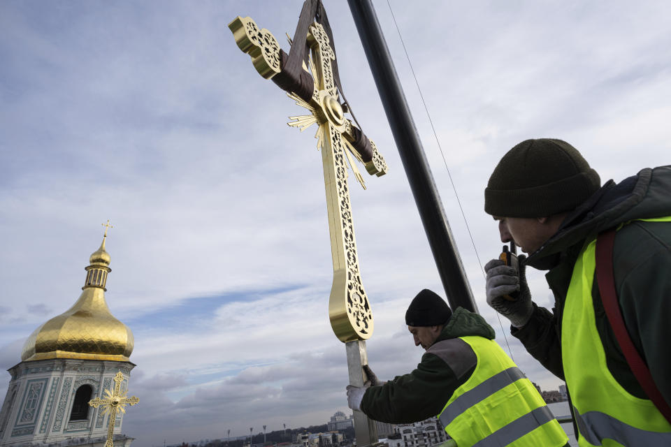 Ihor Kuzmenko, left, and Yuriy Maliuh altitude workers install a restored cross on a dome of Saint Sophia Cathedral in Kyiv, Ukraine, Thursday, Dec. 21, 2023. A UNESCO World Heritage site, the gold-domed St. Sophia Cathedral, located in the heart of Kyiv, was built in the 11th century and designed to rival the Hagia Sophia in Istanbul. (AP Photo/Evgeniy Maloletka)