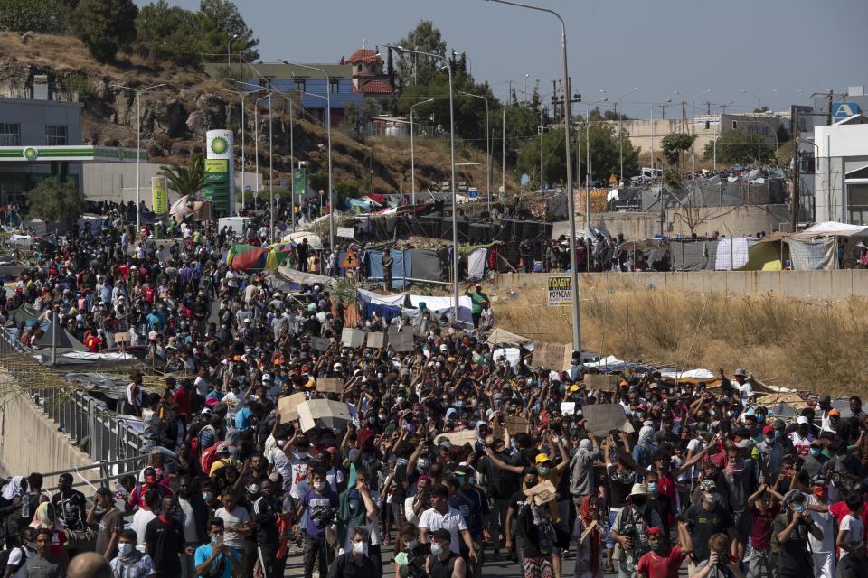 Migrants take part in a rally near Mytilene town, on the northeastern island of Lesbos, Greece, Friday, Sept. 11, 2020. Thousands of protesting refugees and migrants left homeless on the Greek island of Lesbos after fires destroyed the notoriously overcrowded Moria camp have gathered on a road leading to the island's main town, demanding to be allowed to leave. (AP Photo/Petros Giannakouris)