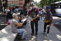 Juan Pablo Lares distributes free copies of a newspaper "Enterate" to people at a bus stop in Caracas, Venezuela, Saturday, July 31, 2021. Two decades of governments that see the press as an enemy have pushed Venezuelan journalists to find alternative ways to keep citizens informed. (AP Photo/Ariana Cubillos)