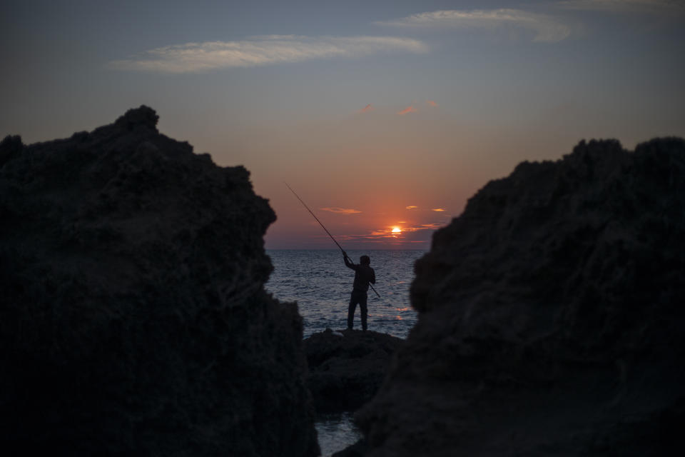 A man collapses his fishing rod as the sun sets over the Mediterranean Sea, in Gador nature reserve near Hadera, Israel, Sunday, Feb. 21, 2021. Israel has closed its Mediterranean beaches following an offshore oil spill that has devastated the country's coastline in what officials are calling one of the country's worst ecological disasters. (AP Photo/Ariel Schalit)