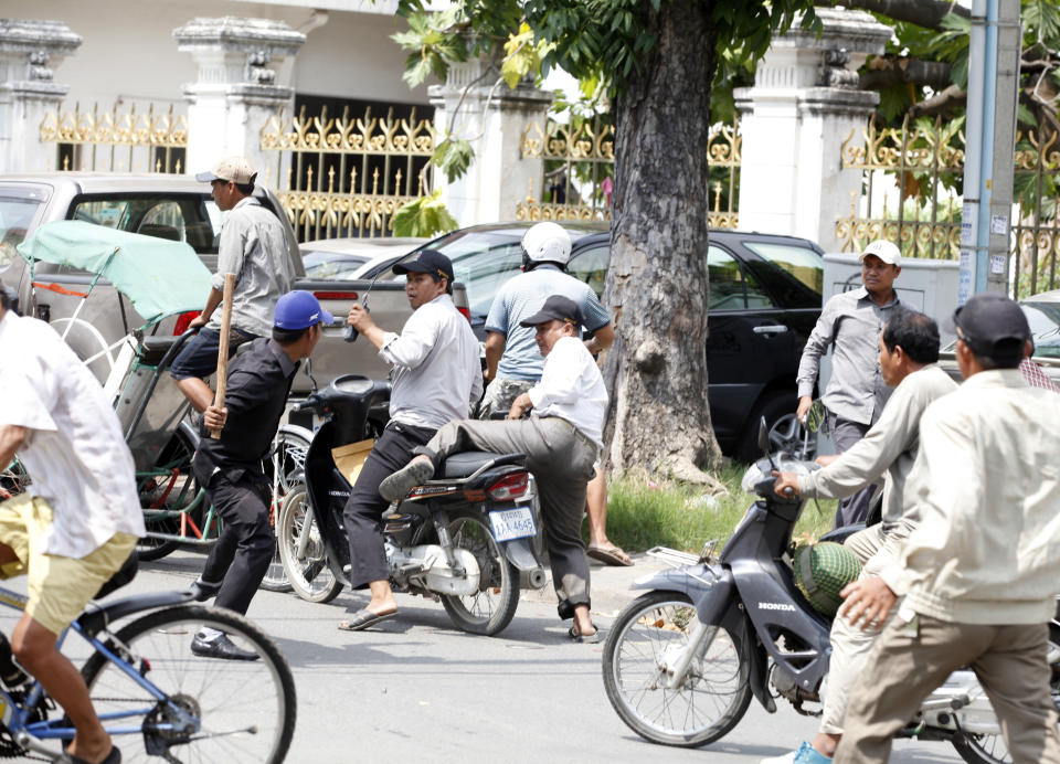 A government security force member, in black clothes, beats a protester outside Freedom Park as other protesters run away in Phnom Penh, Cambodia, Thursday, May 1, 2014. Security forces have beaten demonstrators after a May day rally held in defiance of a government ban on public protests in the Cambodian capital. Nearly 1,000 factory workers and supporters of the opposition Cambodia National Rescue Party had gathered on the streets outside the city's Freedom Park, which had been barred to demonstrators and sealed off. (AP Photo)