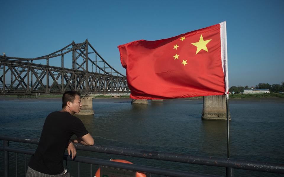 A Chinese tourist looking out over the Yalu River between North Korea and China - NICOLAS ASFOURI /AFP