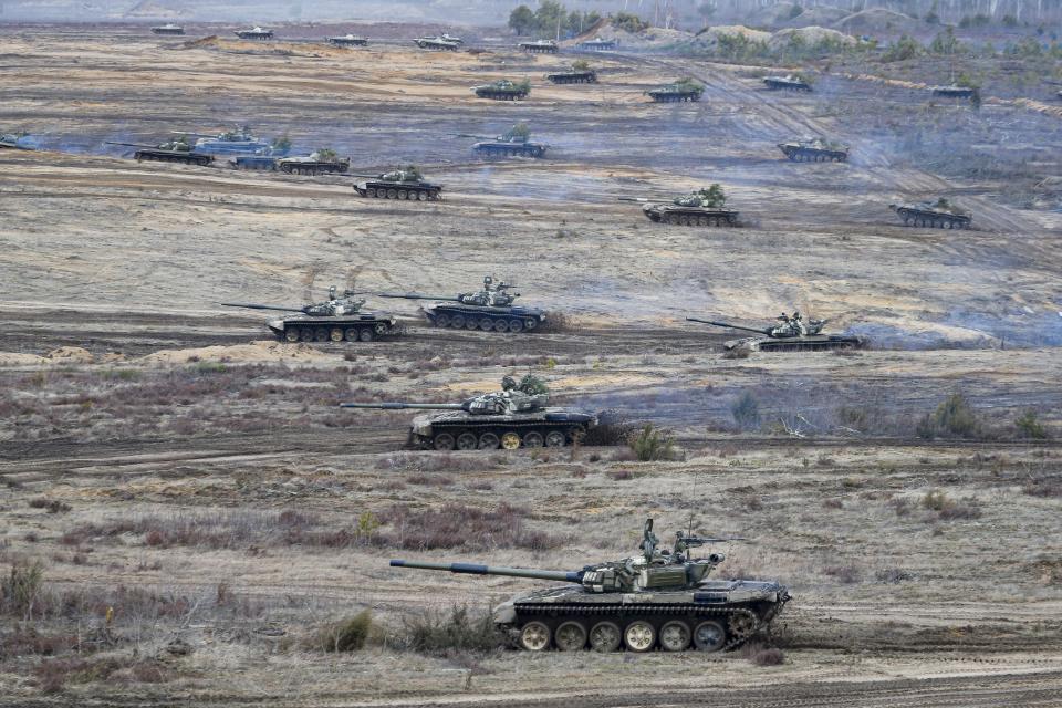 A score of Russian tanks in a series of parallel paths make their way across rough ground.