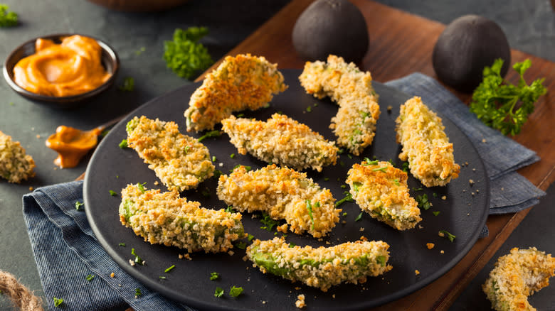 breaded and fried avocados on a dark plate