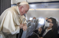 Pope Francis greets the journalists onboard the papal plane on the occasion of his five-day pastoral visit to Cyprus and Greece, Monday, Dec. 6, 2021. Francis' five-day trip to Cyprus and Greece has been dominated by the migrant issue and Francis' call for European countries to stop building walls, stoking fears and shutting out "those in greater need who knock at our door." (Alessandro Di Meo/Pool photo via AP)