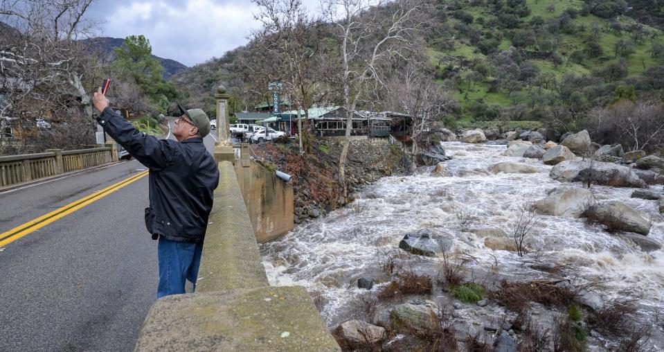 Candelario Mellan of Lindsay takes a selfie Tuesday, January 10, 2023 from Pumpkin Hallow Bridge as the Kaweah River rushes by the Gateway Restaurant in Three Rivers.