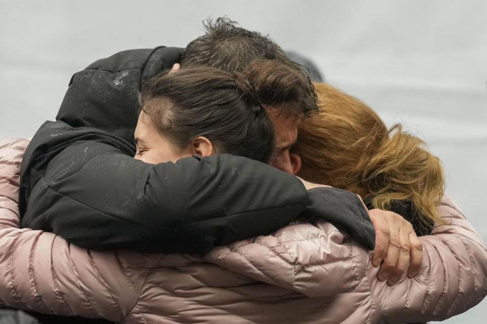 People cry in front of the Vladislav Ribnikar school during a memorial ceremony to mark the first anniversary of a shooting that killed 10 people in Belgrade, Serbia, Friday, May 3, 2024. (AP Photo/Darko Vojinovic)