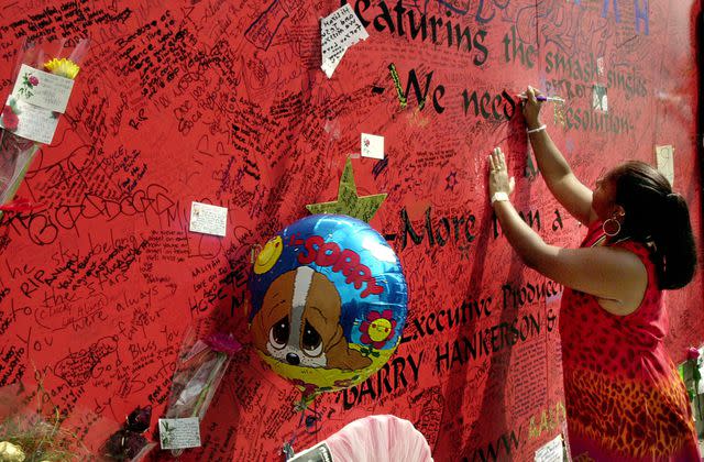 <p>Steve Grayson/WireImage</p> A fan of R&B singer/actress Aaliyah signs a record store mural of the late singer in what has become a shrine dedicated to her.