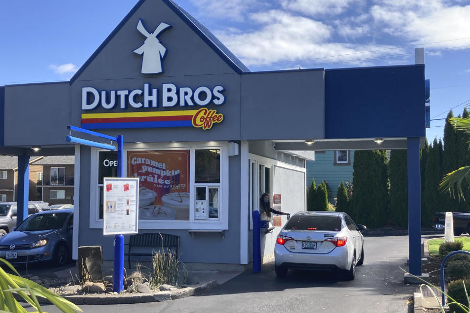 An employee of Dutch Bros Coffee in Salem, Ore., hands a drink to a customer on Wednesday, Sept. 15, 2021. After humble beginnings as a pushcart operation decades ago in an Oregon town and growing into a company with hundreds of drive-thru coffee shops in about a dozen U.S. states, Dutch Bros Coffee on Wednesday launched an initial public offering on the New York Stock Exchange. (AP Photo/Andrew Selsky)