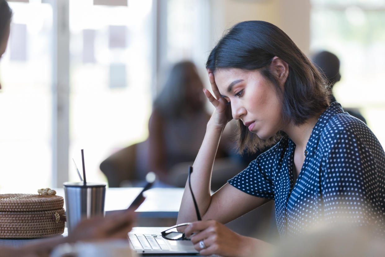 The mid adult woman is distressed by the problem she is having with her laptop. colleagues