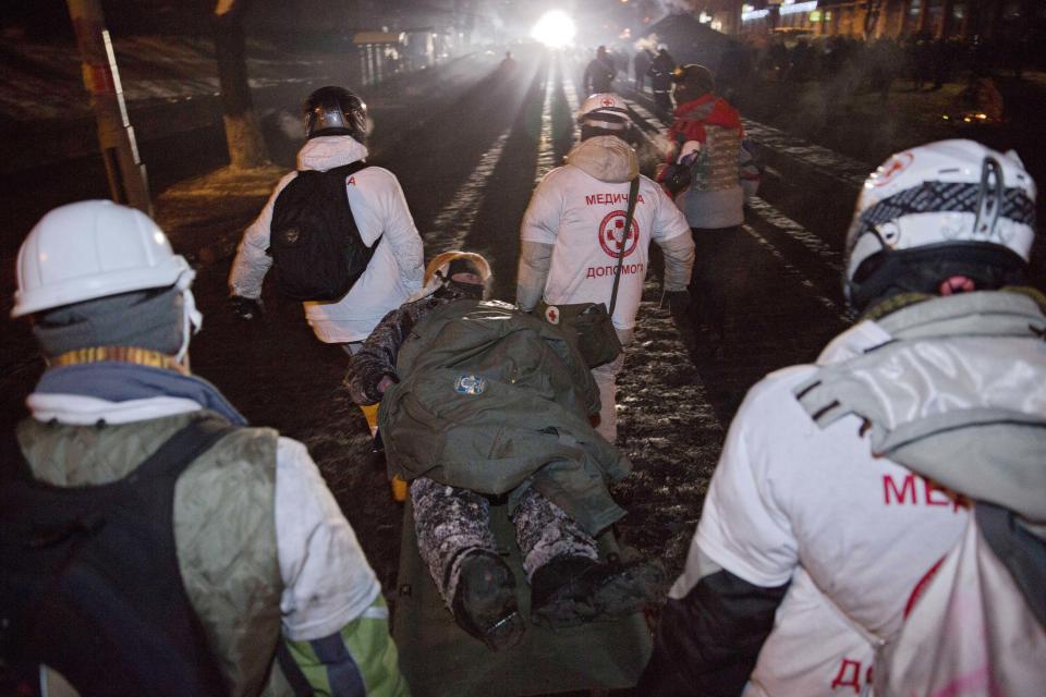 Medics transport an injured protester during an attack of the Ukrainian House building in central Kiev, Ukraine, early Sunday, Jan. 26, 2014. New violence erupted in Ukraine's capital during the night as a large crowd attacked the government exposition and conference hall where police were stationed inside. Early Sunday, demonstrators were throwing firebombs into the Ukrainian House building and setting off fireworks, and police responded with tear gas. (AP Photo/Evgeny Feldman, Novaya Gazeta)