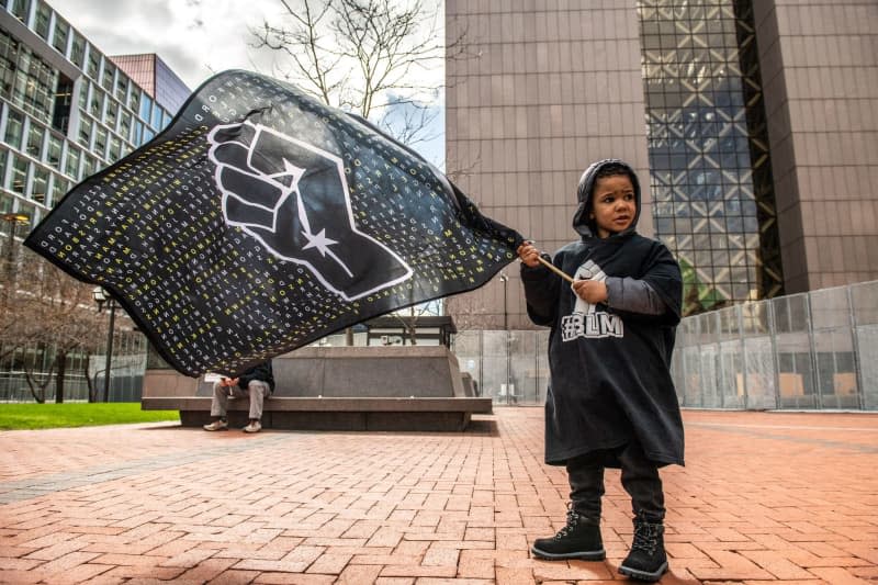 A child holds a Black Lives Matter flag outside the Hennepin County Courthouse a day before the trial of Minneapolis police Officer Derek Chauvin in the death of George Floyd. imageSPACE via ZUMA Wire/dpa