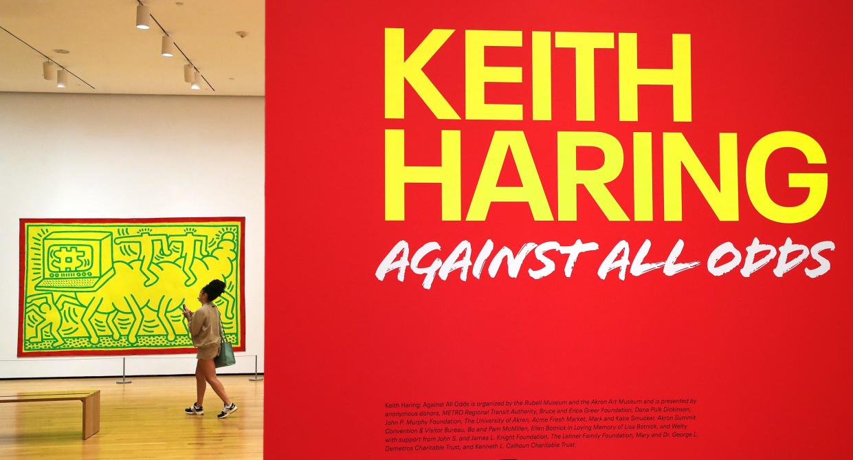 A museum guest walks past an untitled piece that depicts a caterpillar with a computer head in the "Keith Haring: Against All Odds" exhibit at the Akron Art Museum.