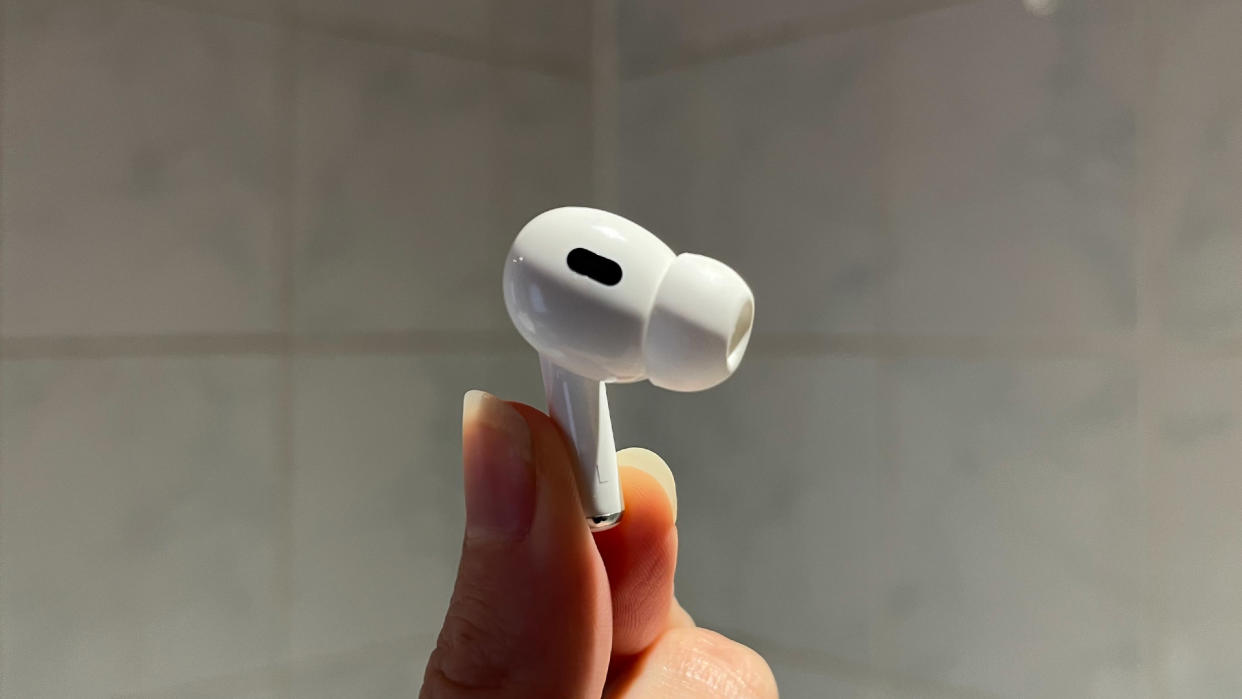  A hand holds a single AirPod. 