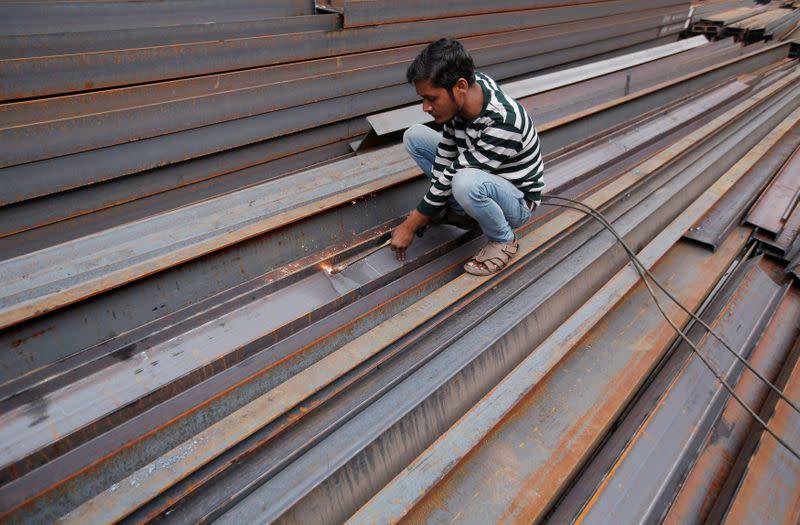 FILE PHOTO: A worker cuts iron rods outside a workshop at an iron and steel market in an industrial area in New Delhi