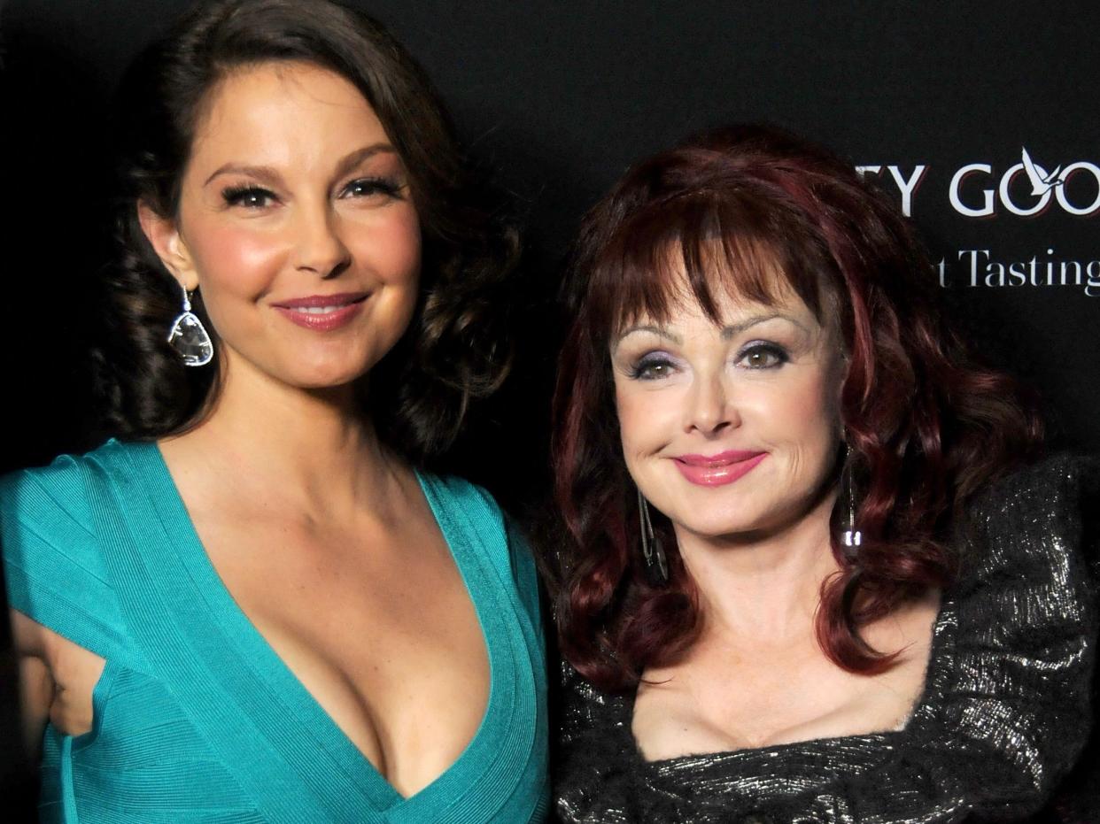 Ashley Judd in a green dress next to Naomi Judd in a dark dress