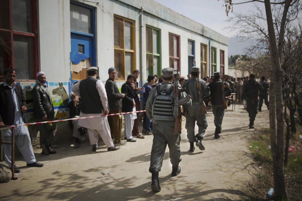 Afghan police men arrive to secure a registration center as men line up to get their registration card on the last day of voter registration for the upcoming presidential elections outside a school in Kabul, Afghanistan, Tuesday, April 1, 2014. Elections will take place on April 5, 2014. (AP Photo/Anja Niedringhaus)