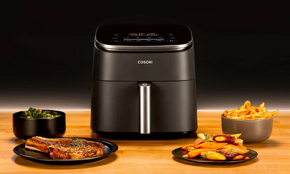 The COSORI Air Fryer 9-in-1 sits on a countertop with food surrounding it. 