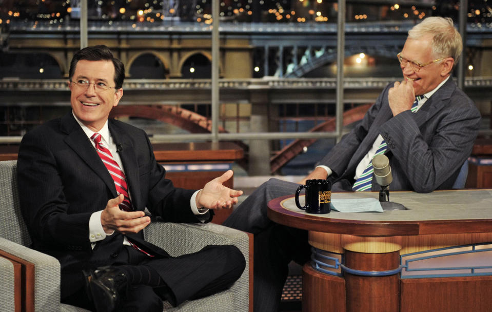 In this May 3, 2012 photo provided by CBS, Stephen Colbert, left, host of the “Colbert Report” on the Comedy Central Network, has a laugh on stage with host David Letterman on the set of the “Late Show with David Letterman,” in New York. Colbert says on a visit to the late-night show he’ll take over next year he’s obviously “thrilled” to be succeeding David Letterman. The Comedy Central host told Letterman on CBS’ “Late Show” on Tuesday, April 22, 2014, he’s going to do whatever Letterman has done. (AP Photo/CBS, John Paul Filo) MANDATORY CREDIT, NO SALES, NO ARCHIVE, FOR NORTH AMERICAN USE ONLY