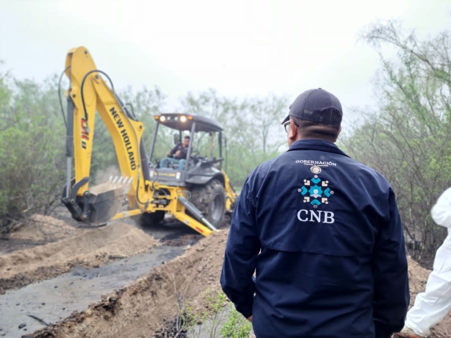 A member of Mexico’s National Search Commission (CNB) watches as a backhoe digs on the site of a presumed clandestine grave in the state of Nuevo Leon.