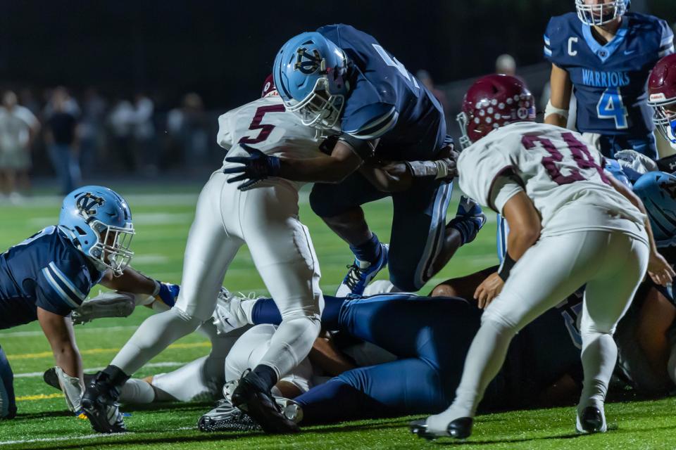 Central Valley running back Mason Dixon (5) leaps over his offensive line to fight his way for extra yards while being wrapped up by Beaver Area's Qualan Cain (5) during the Warriors Western Hills Conference matchup against the Bobcats Friday night at Sarge Alberts Stadium.