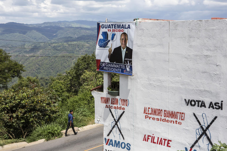 A man walks on the side of a road past a house displaying political propaganda of presidential candidate Alejandro Giammattei of the Vamos party, in San Martin Jilotepeque, Sunday, August 4, 2019. Guatemalans head to the polls on Sunday to elect a new president. (AP Photo/ Oliver de Ros)