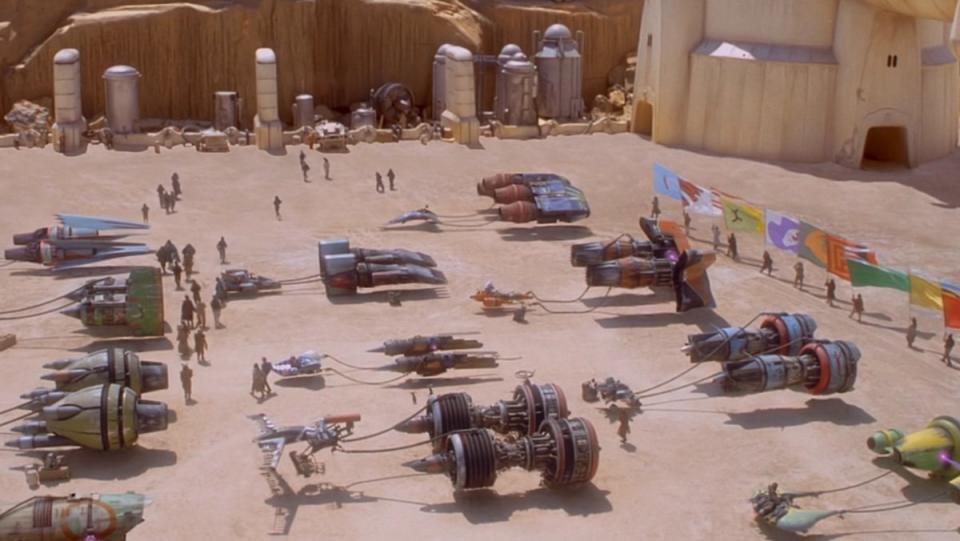 The podracers line up for the Boonta Eve Classis in front of flag bearers in The Phantom Menace