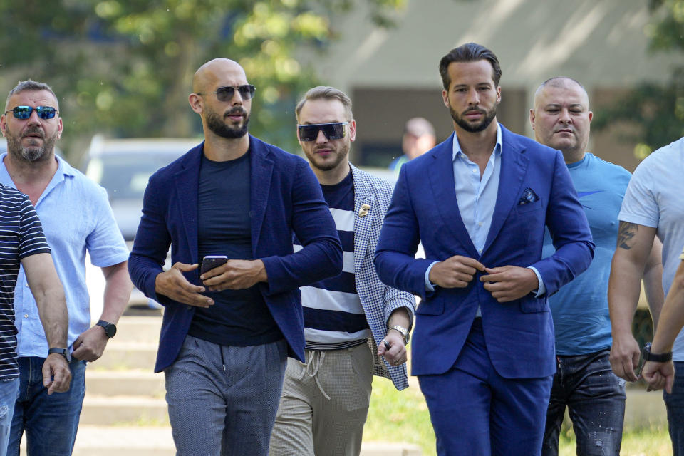 Andrew Tate, left, and his brother Tristan, arrive flanked by bodyguards, at the Bucharest Tribunal where judges will decide if they will remain under house arrest for another 30 day period, in Bucharest, Romania, Monday, July 17, 2023. On June 20, 2023, Romanian prosecutors charged the Tate brothers and two other suspects with human trafficking, rape and organizing a criminal group for the sexual exploitation of women. (AP Photo/Andreea Alexandru)