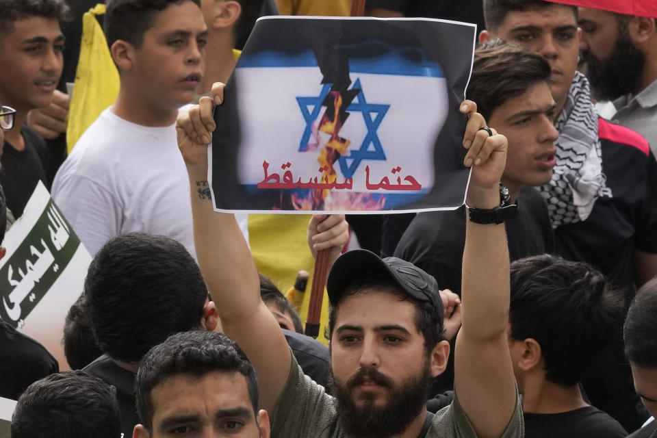 A Hezbollah supporter holds up an Arabic placard that reads:"It will definitely fall," during a protest to show their solidarity with the Palestinians, in the southern suburb of Beirut, Lebanon, Friday, Oct. 13, 2023. Tens of thousands of Muslims demonstrated Friday across the Middle East in support of the Palestinians and against Israeli airstrikes pounding Gaza, underscoring the risk of a wider regional conflict erupting as Israel prepares for a possible ground invasion in the coastal strip. (AP Photo/Hussein Malla)