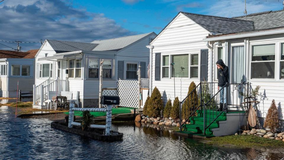 PHOTO: A woman looks at the flood waters around her house, Jan. 10, 2024, in Hampton, N.H. (Joseph Prezioso/AFP via Getty Images)