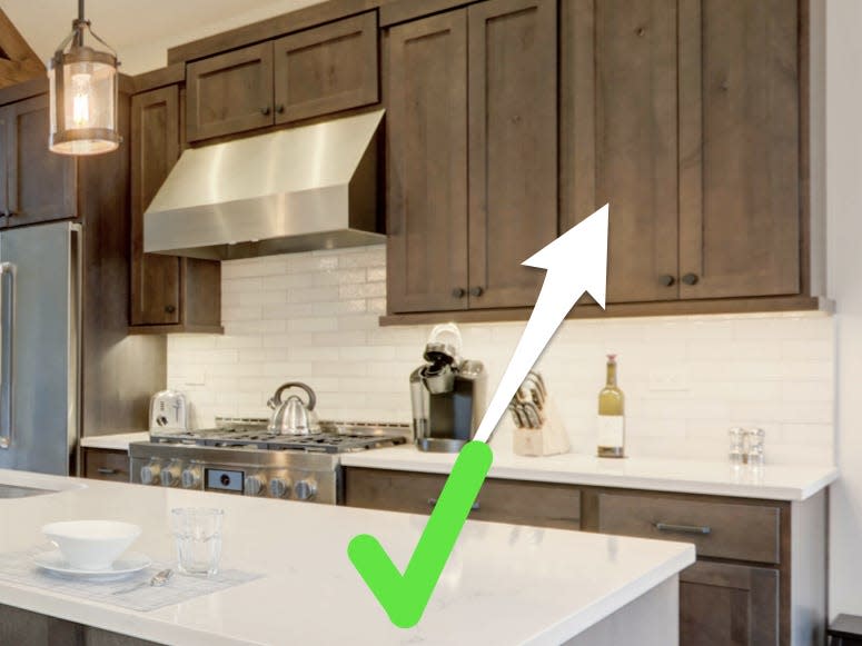 Kitchen with green checkmark pointing to unpainted cabinets