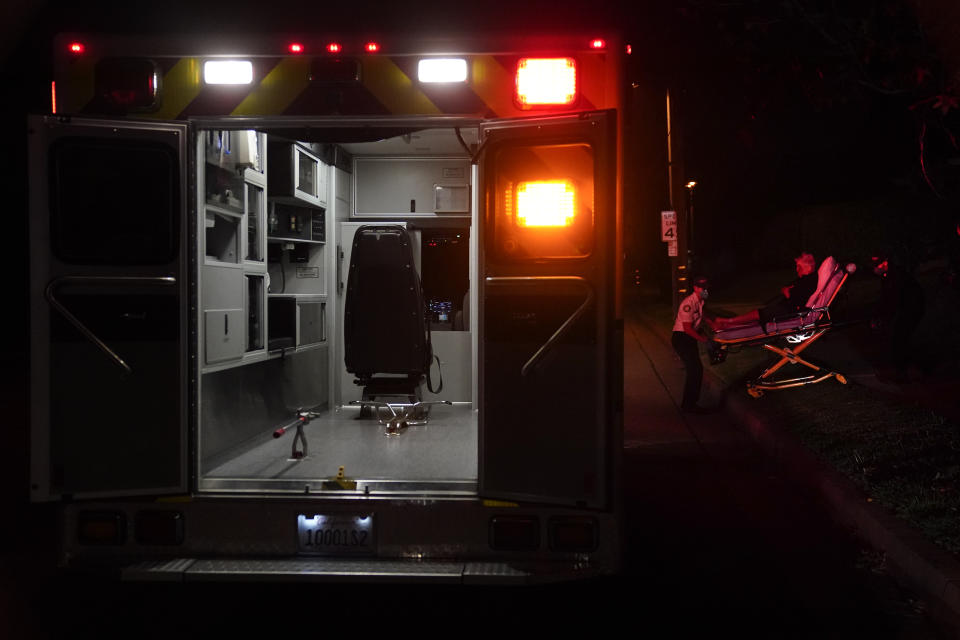 Emergency medical technicians Thomas Hoang and Joshua Hammond, of Emergency Ambulance Service, transport a patient on a gurney in Placentia, Calif., Friday, Jan. 8, 2021. EMTs and paramedics have always dealt with life and death — they make split-second decisions about patient care, which hospital to race to, the best and fastest way to save someone — and now they're just a breath away from becoming the patient themselves. (AP Photo/Jae C. Hong)